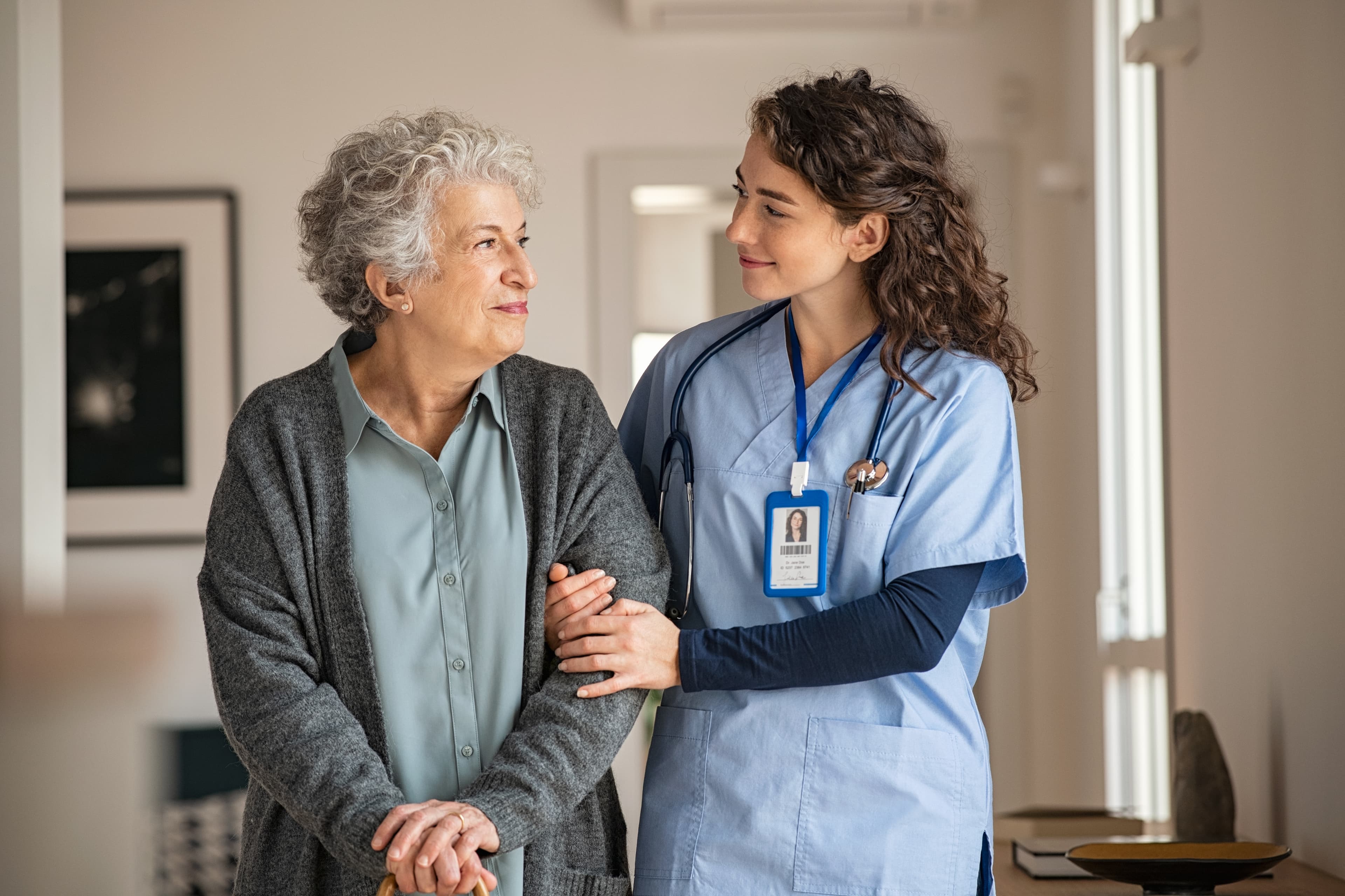 Elderly woman walking arm-in-arm with a carer